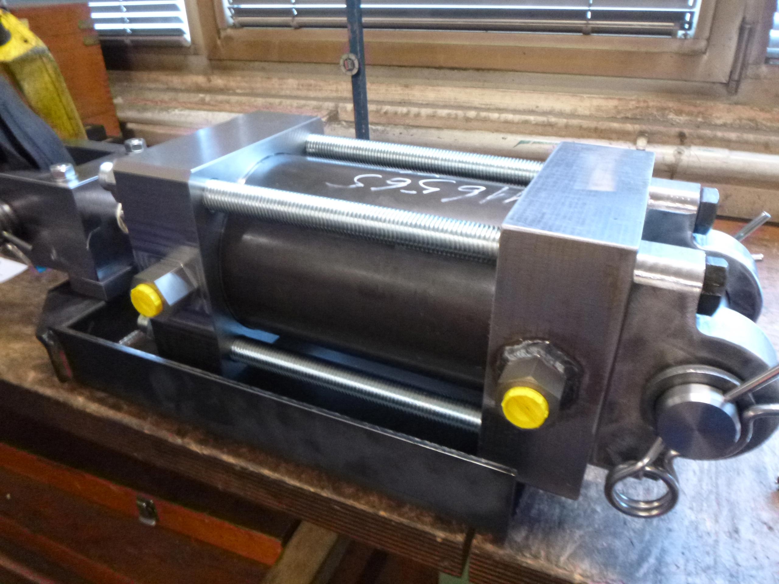 Ein silberner Metallzylinder auf einem Tisch mit gelber Schraubenkappe.